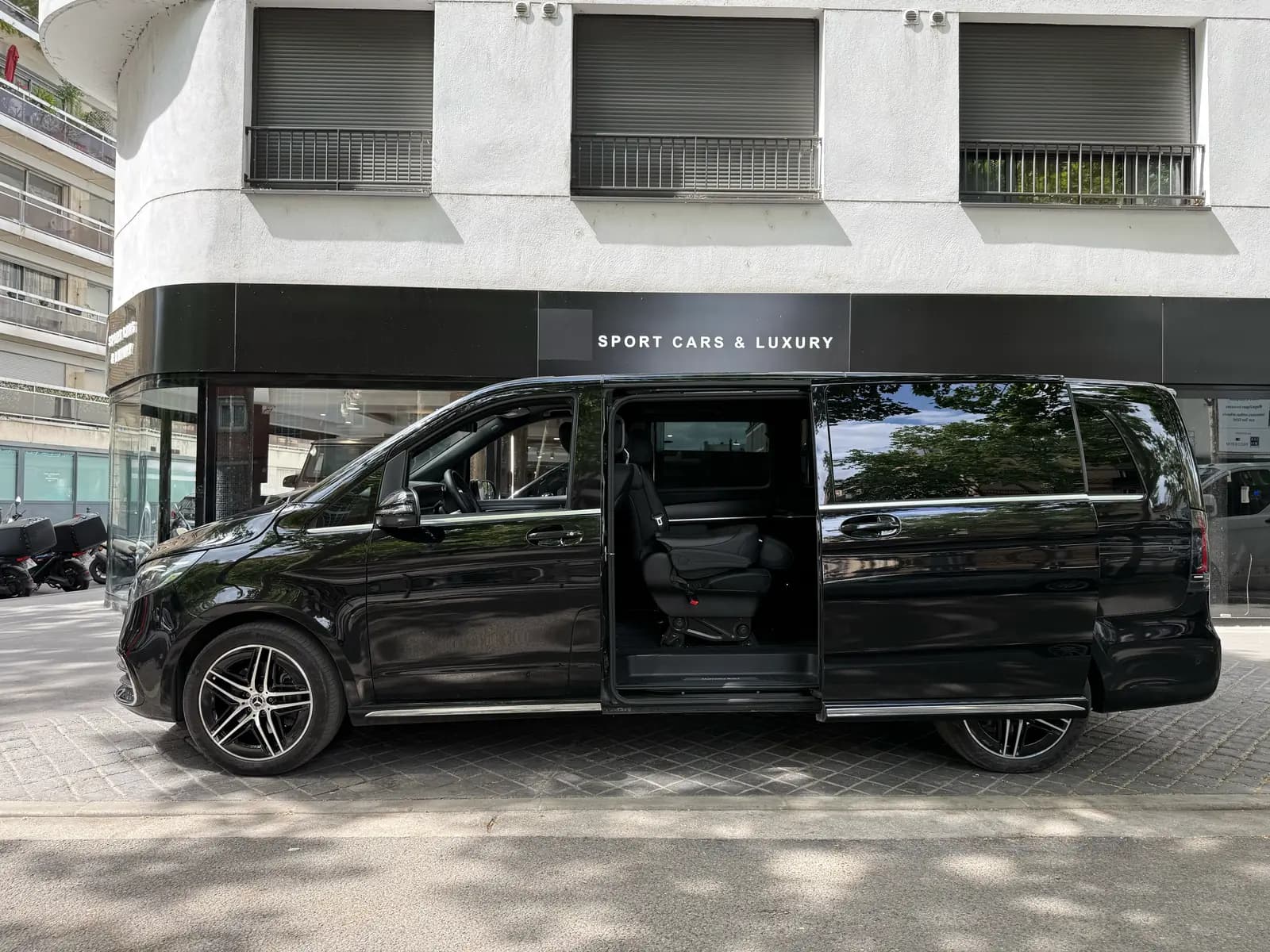 Van Mercedes Classe V noir vu de profil, porte latérale coulissante ouverte sur l'espace passagers